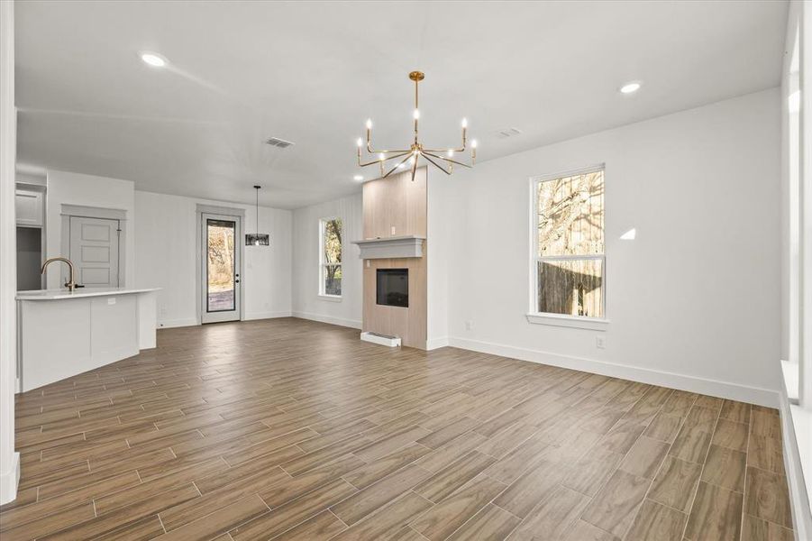 Unfurnished living room featuring an inviting chandelier, sink, and a tile fireplace