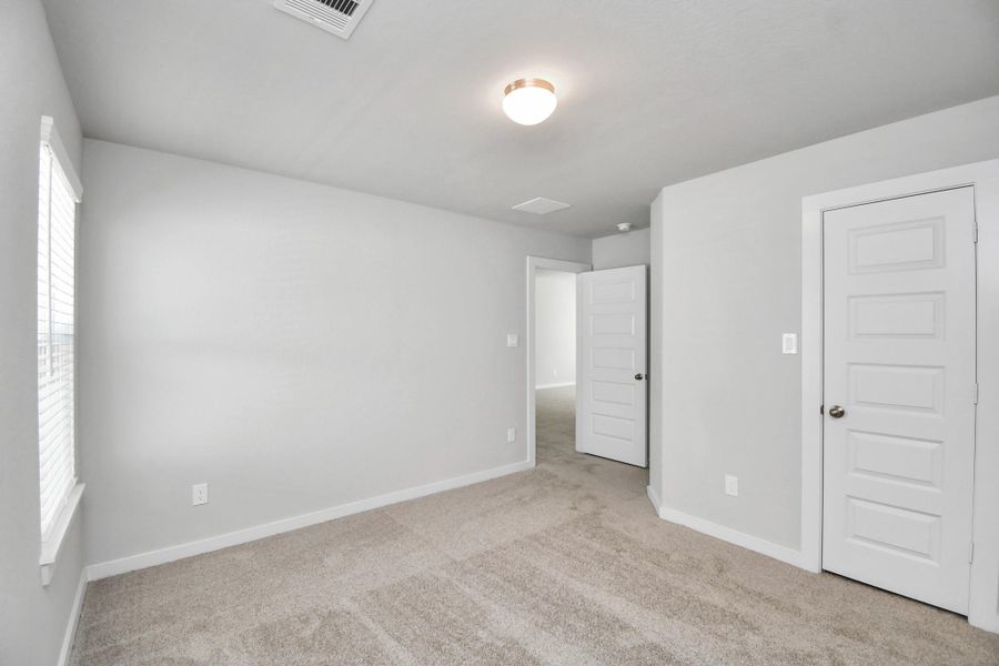 Secondary bedroom features plush carpeting, large windows that let in plenty of natural light, bright paint, and spacious closets. Sample photo of completed home with similar floor plan. Actual colors and selections may vary.