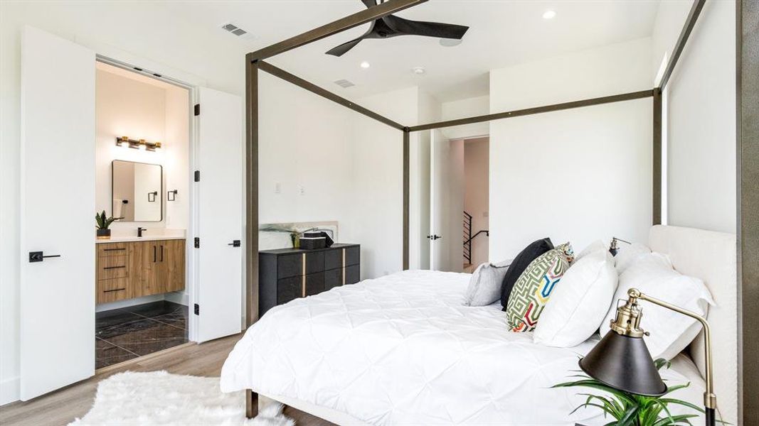 Tiled bedroom featuring ceiling fan and ensuite bath