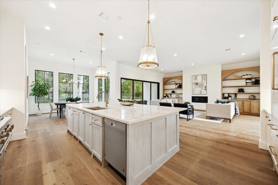 Open-concept living with a large kitchen island, white oak wood floors, and a bright living and dining area overlooking the backyard.