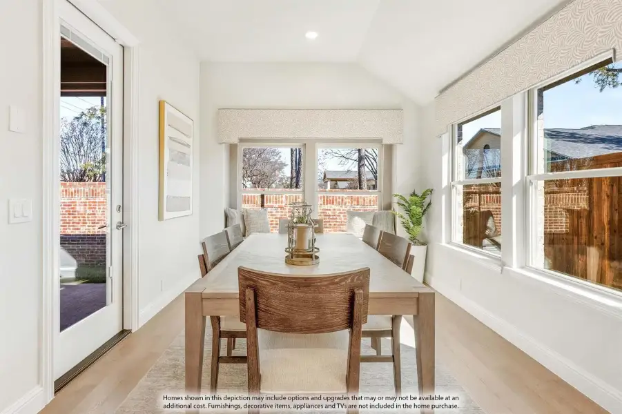 Bright dining room with wood table, vaulted ceiling, large windows, and glass door to backyard