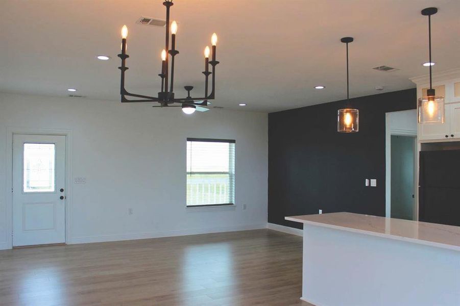 Kitchen with white cabinets, hanging light fixtures, healthy amount of natural light, light stone countertops, and recessed lighting Kitchen with white cabinets, hanging light fixtures, healthy amount of natural light, light stone countertops, and recessed lighting
