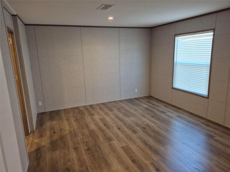 Spare room featuring wood finished floors, a decorative wall, crown molding, and recessed lighting