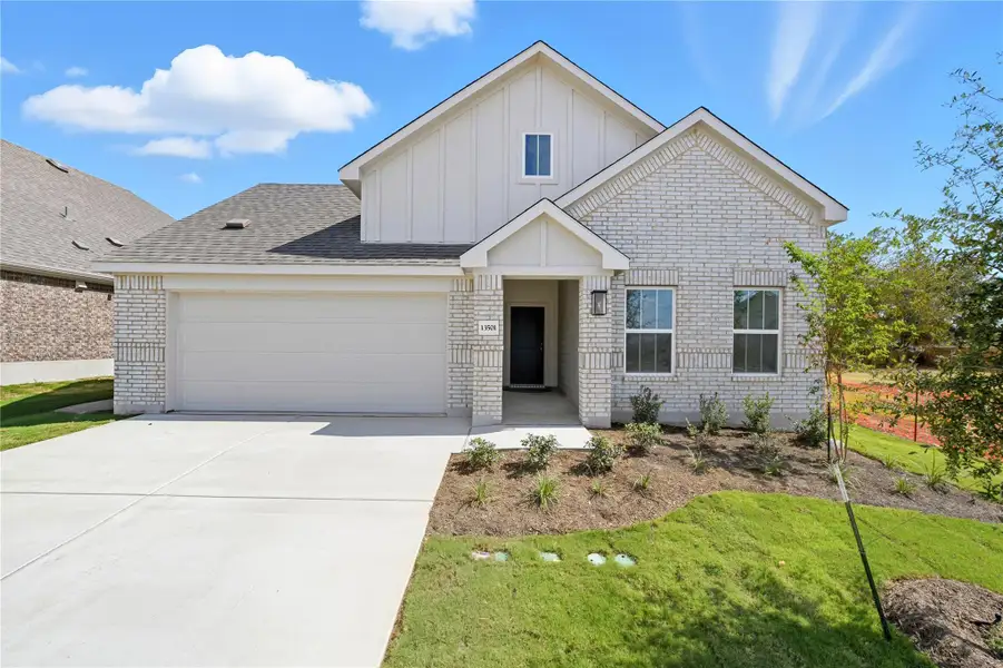 View of front of property featuring brick siding, board and batten siding, concrete driveway, a front yard, and a garage View of front of property featuring brick siding, board and batten siding, concrete driveway, a front yard, and a garage