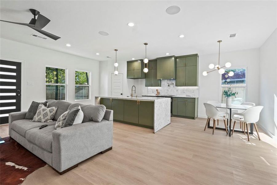 Living area with a chandelier, light wood-style floors, a ceiling fan, healthy amount of natural light, and recessed lighting