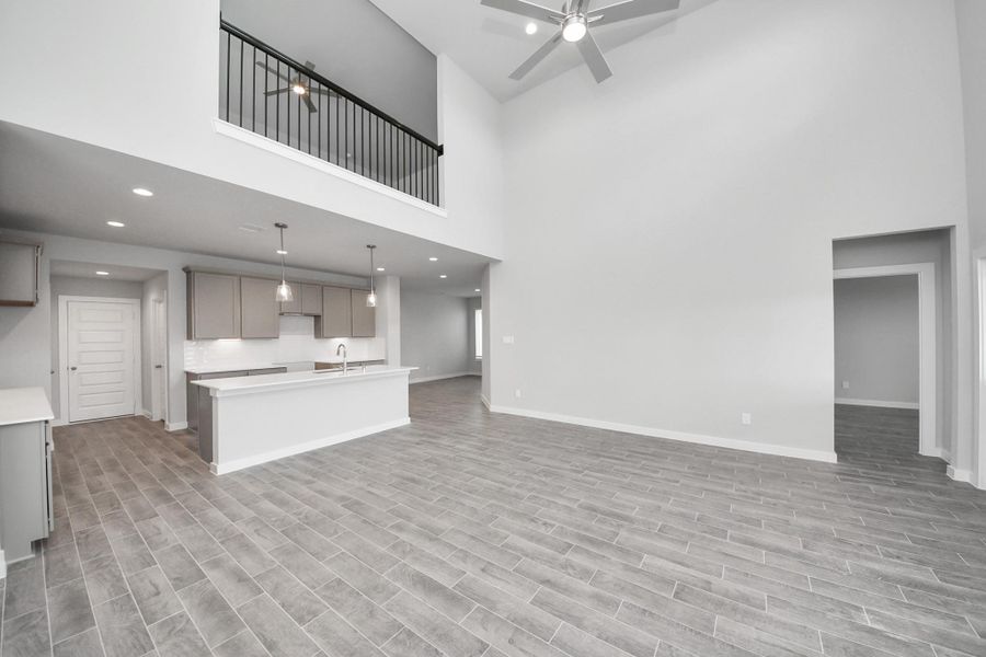 Gather the family and guests together in your lovely living room! Featuring soaring high ceilings, recessed lighting, ceiling fan, custom paint, gorgeous floors, and large windows that provide plenty of natural lighting throughout the day. Sample photo of completed home with similar floor plan. Actual colors and selections may vary.