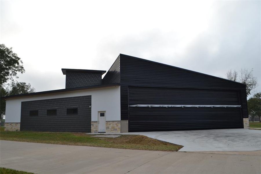 View of property exterior featuring stone siding, stucco siding, and driveway View of property exterior featuring stone siding, stucco siding, and driveway