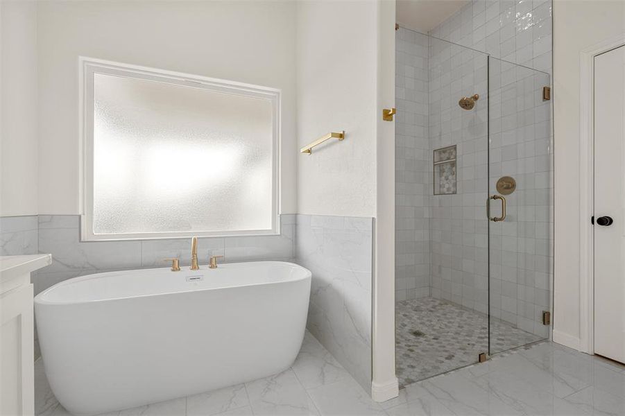 Bathroom featuring a wainscoted wall, a freestanding tub, a stall shower, tile walls, and vanity Bathroom featuring a wainscoted wall, a freestanding tub, a stall shower, tile walls, and vanity