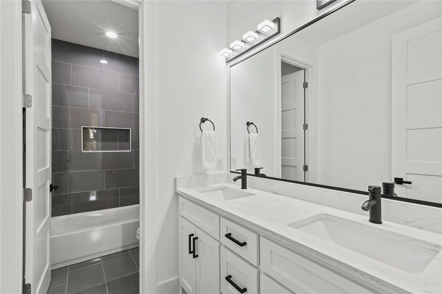 Bathroom with double vanity, shower / bathing tub combination, a sink, and tile patterned floors