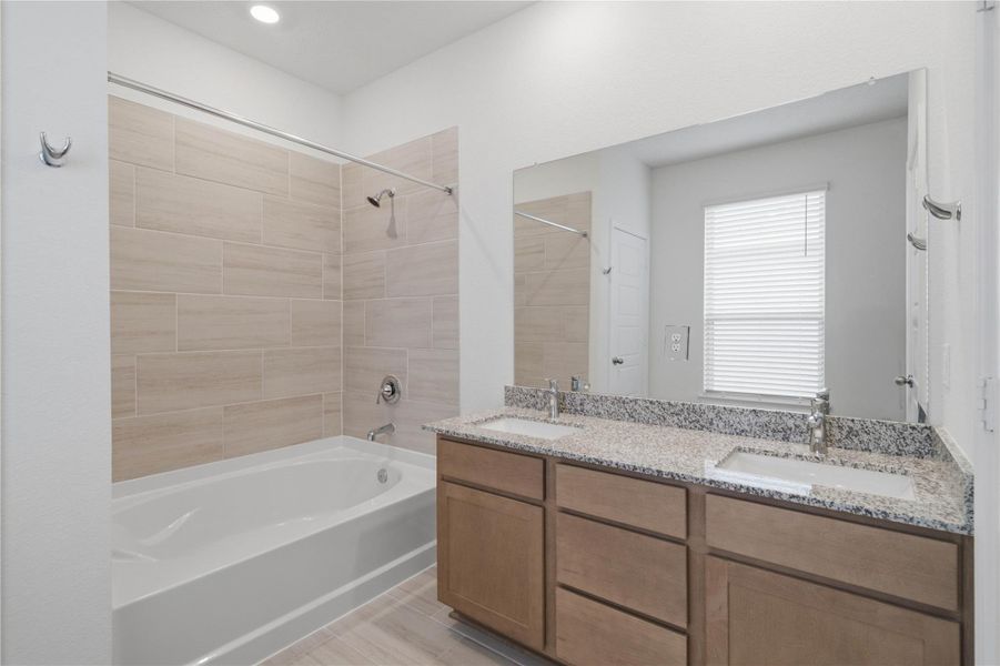 This stunningly updated primary bathroom is truly move-in ready! It features stained cabinetry with light countertops, dual sinks, a large mirror, high ceilings, custom paint, and sleek modern finishes throughout.