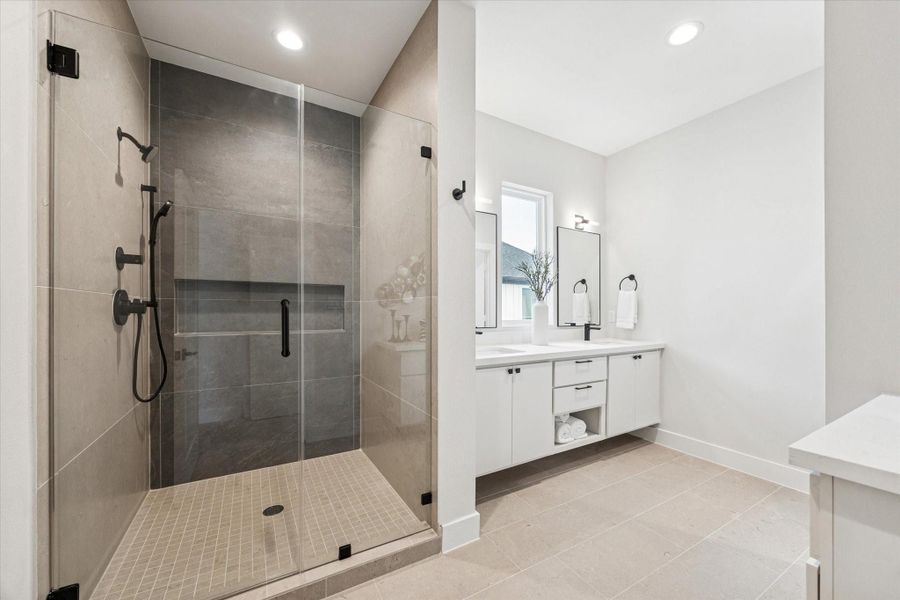 Spa-inspired primary bath featuring double sinks, floating cabinetry, and a large glass-enclosed shower with both a standard and handheld shower head.