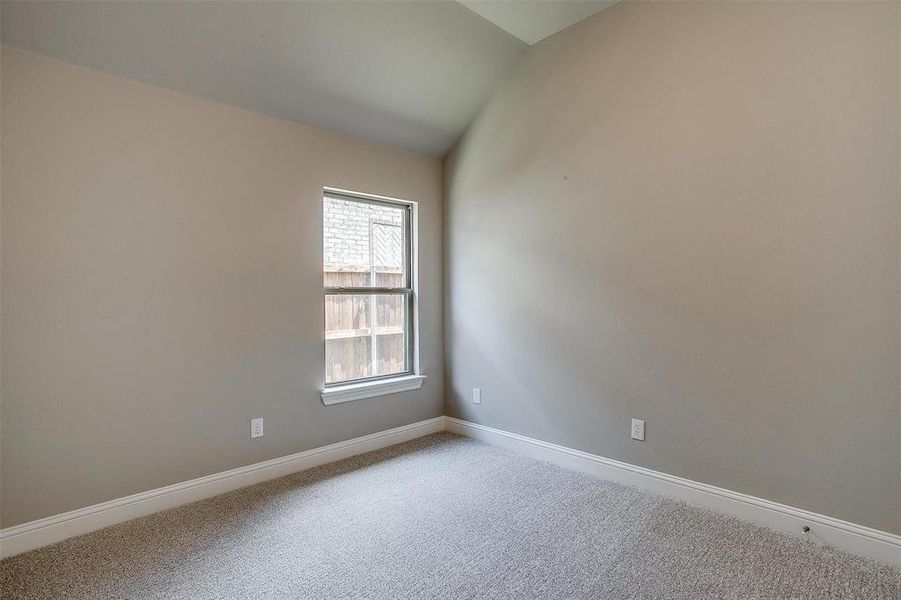 Unfurnished room featuring carpet flooring and lofted ceiling