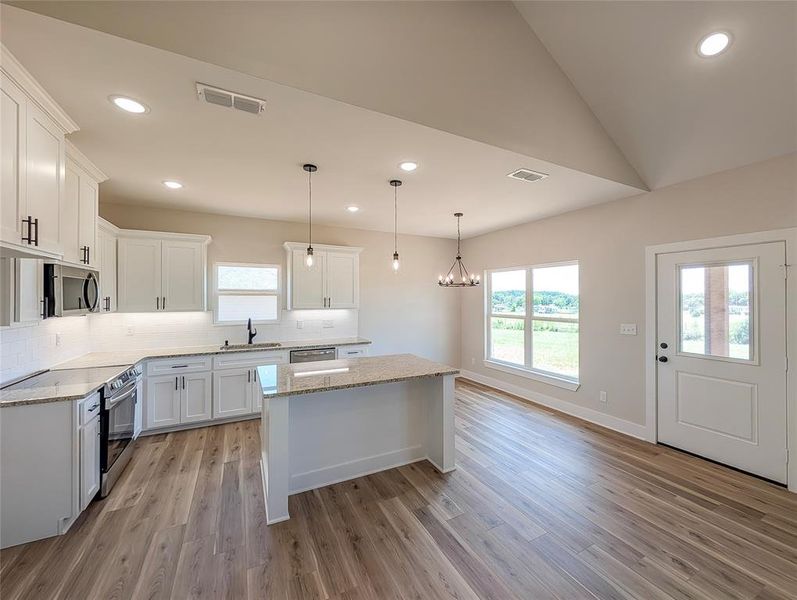 Kitchen with stainless steel appliances, a center island, backsplash, light wood-style flooring, and recessed lighting Kitchen with stainless steel appliances, a center island, backsplash, light wood-style flooring, and recessed lighting