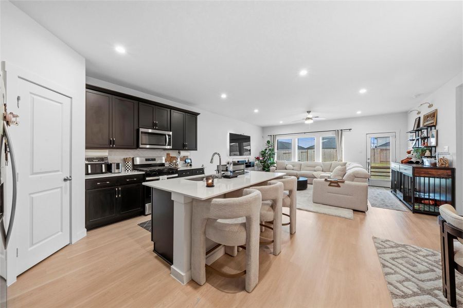 The open-concept design effortlessly blends the kitchen and living spaces, highlighted by a large island with seating, sleek dark cabinetry, and a wall of windows that brings in abundant natural light. The open-concept design effortlessly blends the kitchen and living spaces, highlighted by a large island with seating, sleek dark cabinetry, and a wall of windows that brings in abundant natural light.