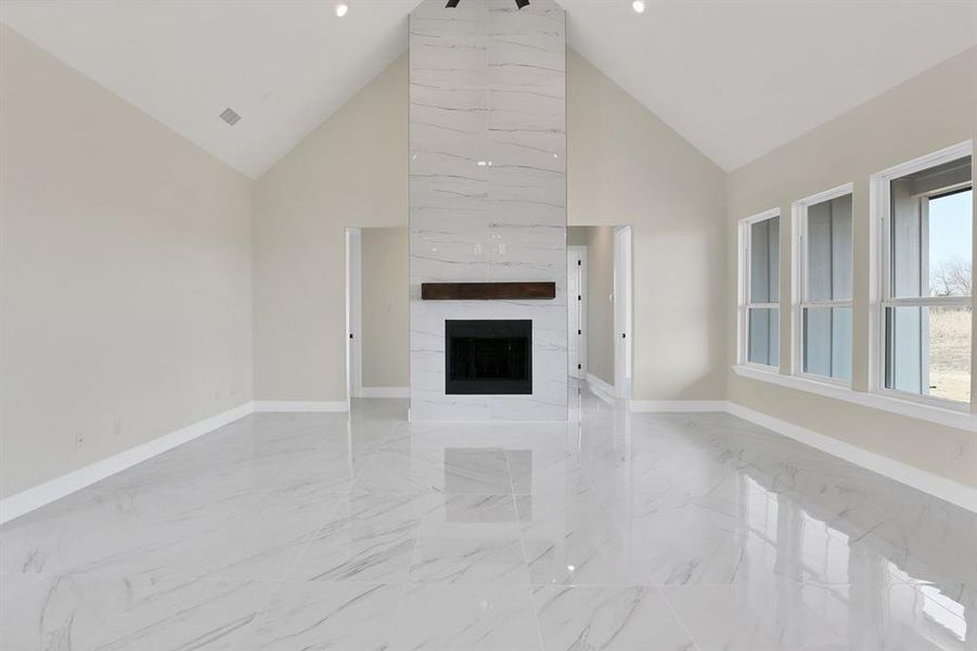 Unfurnished living room featuring a large fireplace and high vaulted ceiling