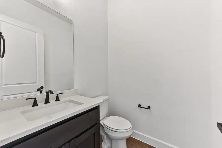 Half bathroom with vanity, dark wood-type flooring, and a textured wall