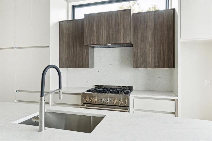 Equipped with a Jenair appliance package, this view of the kitchen accentuates the mix of warm and cool tones with natural light, to make the space feel modern and inviting.