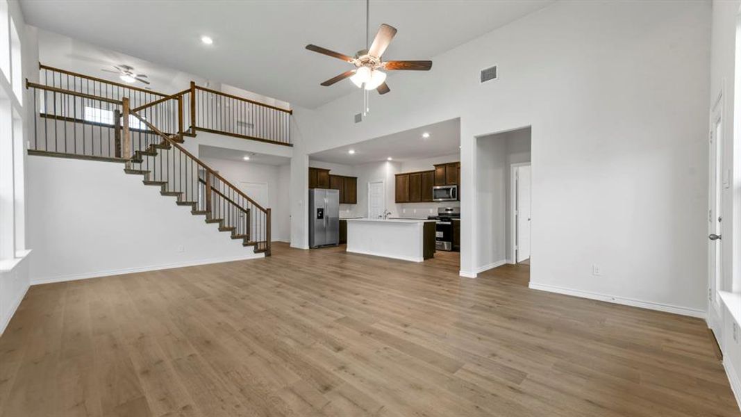 Unfurnished living room featuring a ceiling fan, a high ceiling, recessed lighting, and dark wood finished floors Unfurnished living room featuring a ceiling fan, a high ceiling, recessed lighting, and dark wood finished floors
