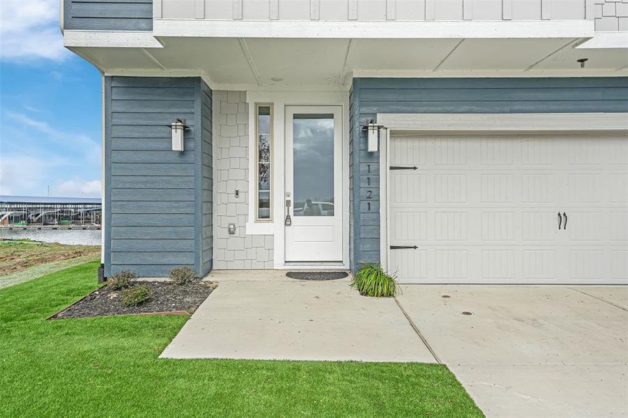 Property entrance with a water view, driveway, and a yard