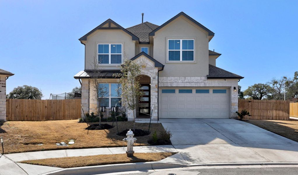 View of front facade featuring stone siding, a shingled roof, an attached garage, and fence