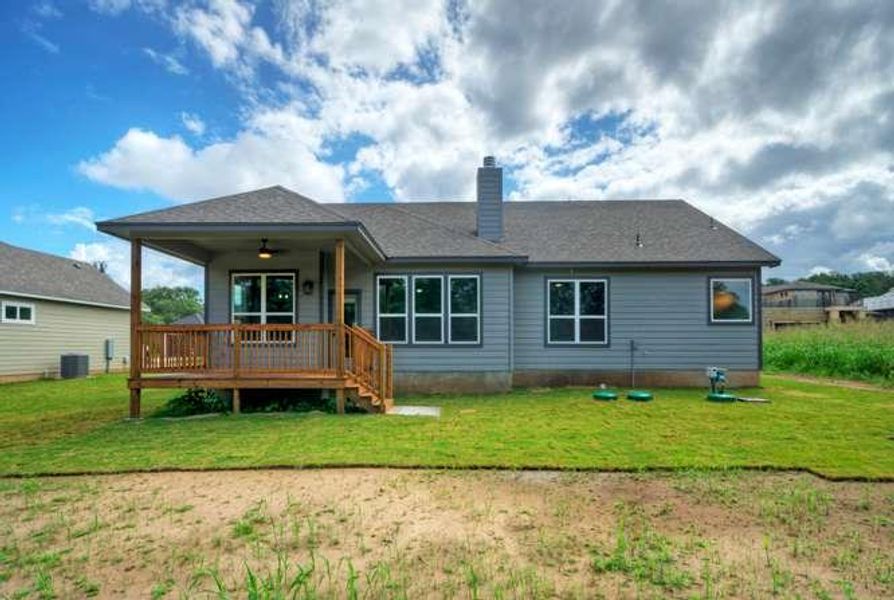 A welcoming rear elevation with a spacious covered patio overlooking a verdant lawn.