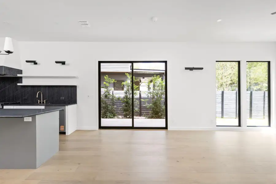 Kitchen with dark countertops, healthy amount of natural light, backsplash, and light wood-type flooring