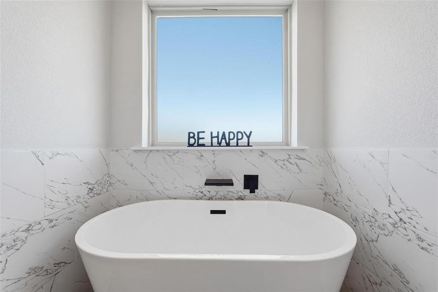Full bathroom featuring a textured wall, a soaking tub, and tile walls