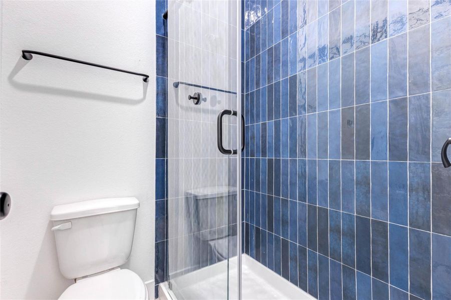 This bathroom features a sleek, modern design with a double vanity in deep blue cabinetry, black fixtures, and a large mirror. The space is bright with white walls and wood flooring, offering a clean, stylish look. This bathroom features a sleek, modern design with a double vanity in deep blue cabinetry, black fixtures, and a large mirror. The space is bright with white walls and wood flooring, offering a clean, stylish look.