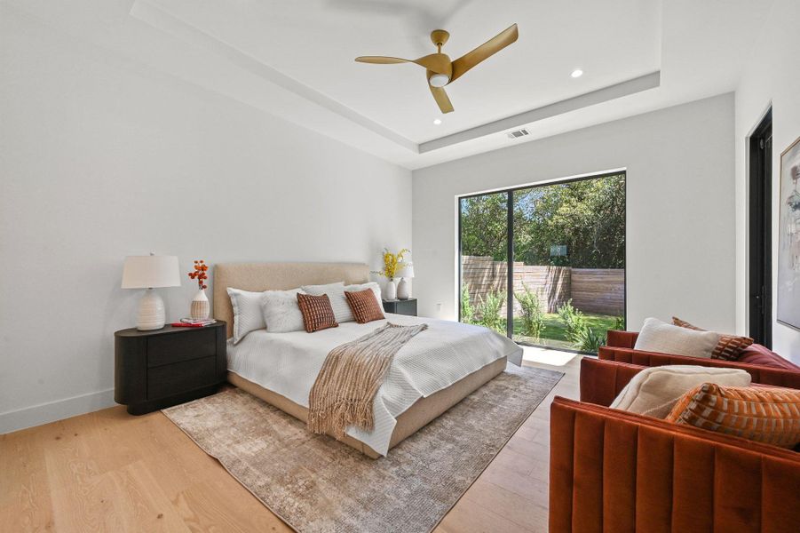 Bedroom with a raised ceiling, light wood-type flooring, a ceiling fan, access to exterior, and recessed lighting