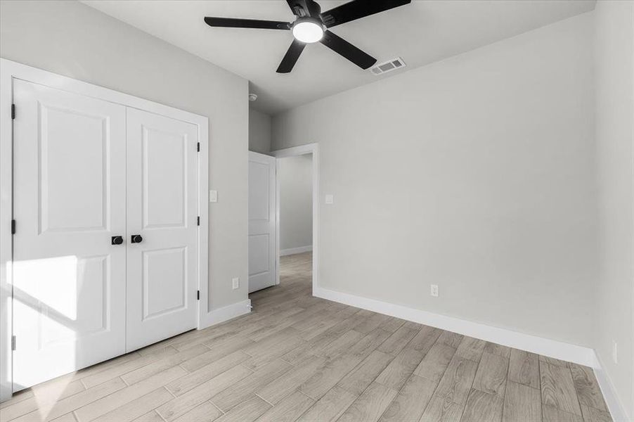 Unfurnished bedroom with a closet, light wood-type flooring, visible vents, and baseboards