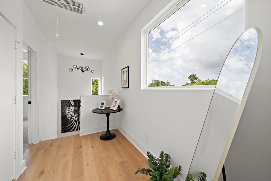 The third-floor hallway offers a statement chandelier suspended above the staircase, creating a stunning focal point. Natural light pours in through nearby windows, highlighting the open layout and elegant finishes that connect the upper level with effortless style. The third-floor hallway offers a statement chandelier suspended above the staircase, creating a stunning focal point. Natural light pours in through nearby windows, highlighting the open layout and elegant finishes that connect the upper level with effortless style.