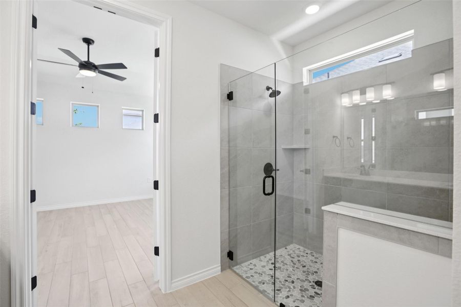 Full bath with a shower stall, light wood-type flooring, and a ceiling fan