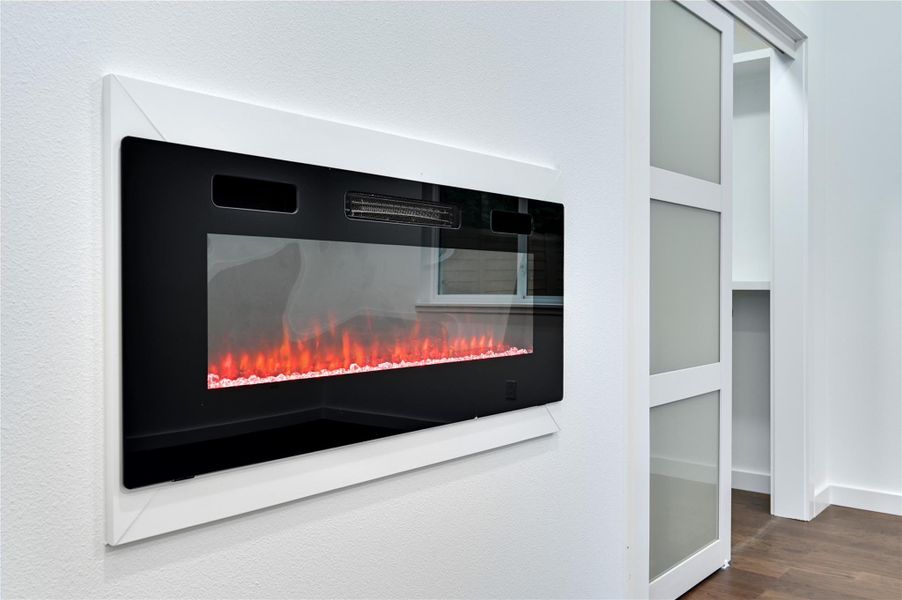 Detailed view of wood finished floors, a lit fireplace, and baseboards
