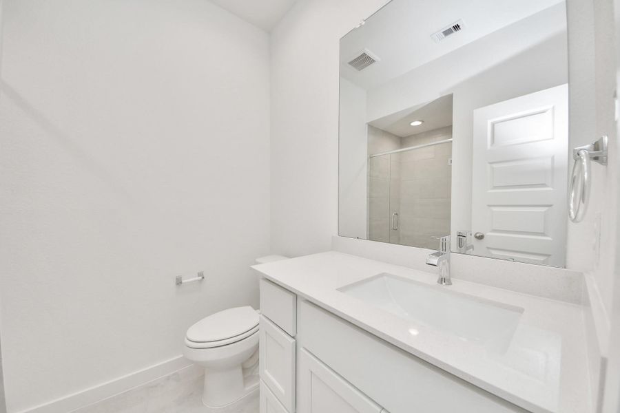 Secondary bath features tile flooring, walk-in shower with tile surround, light stained wood cabinets, beautiful light countertop. Secondary bath features tile flooring, walk-in shower with tile surround, light stained wood cabinets, beautiful light countertop.