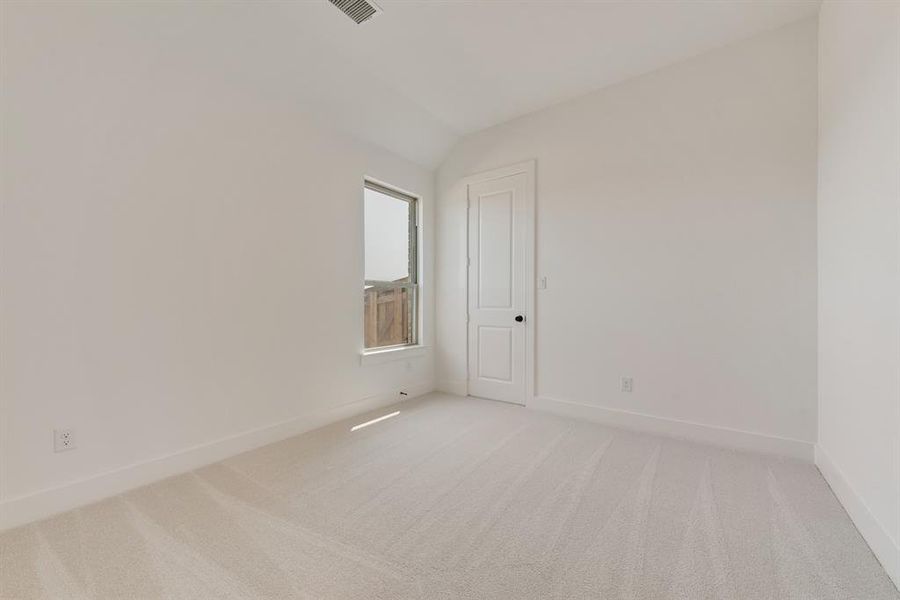 Unfurnished room featuring light carpet and lofted ceiling