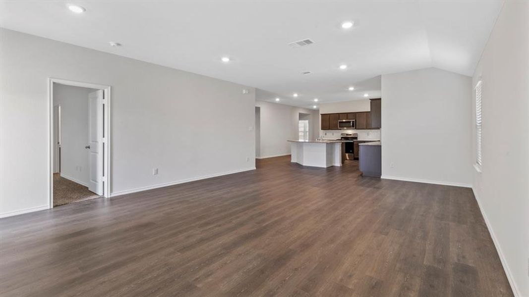 Unfurnished living room with recessed lighting, dark wood finished floors, and vaulted ceiling