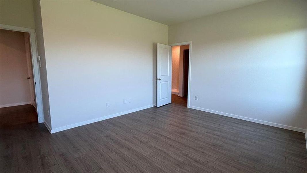 Spacious room featuring wood-finish flooring, light-toned walls, and white trim Spacious room featuring wood-finish flooring, light-toned walls, and white trim