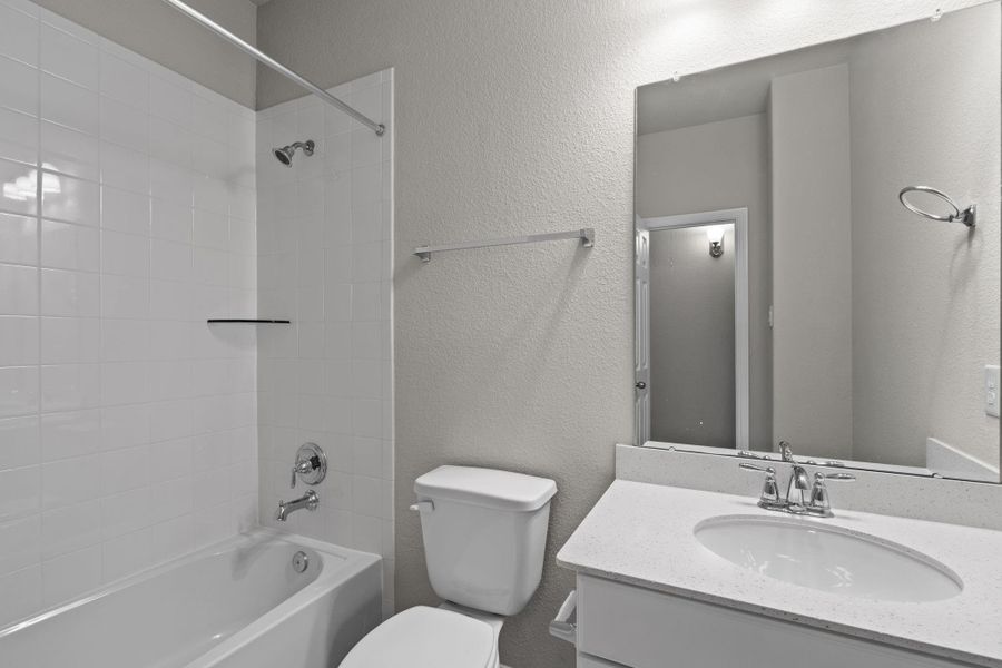 The secondary bath features tile flooring, white cabinetry and light countertops and a shower/tub combo. Perfect for accommodating any visiting family and friends.