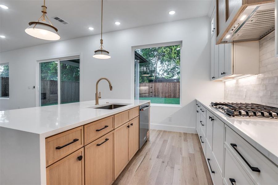 Kitchen featuring recessed lighting, premium range hood, light wood-type flooring, light countertops, and light brown cabinets Kitchen featuring recessed lighting, premium range hood, light wood-type flooring, light countertops, and light brown cabinets