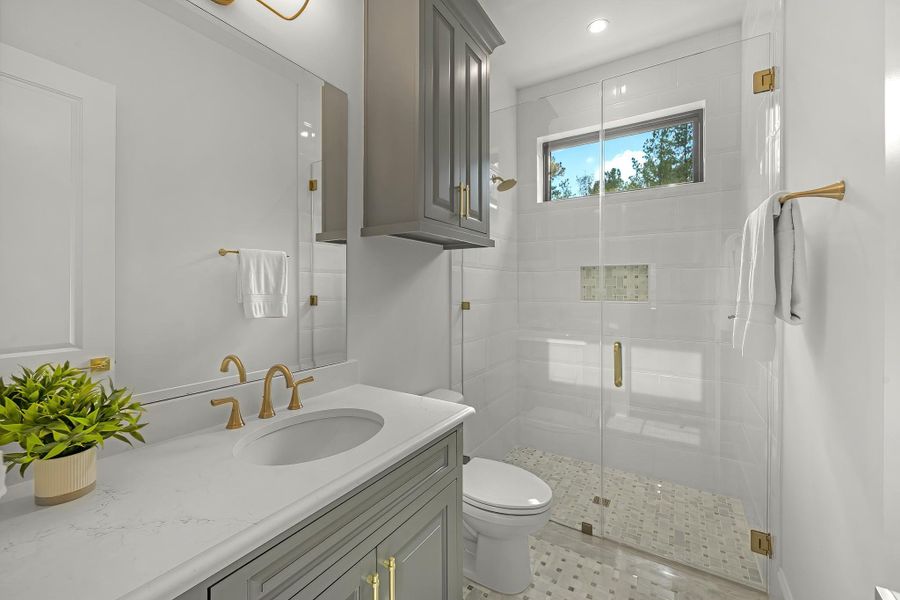 The secondary bath features tile flooring, custom stained cabinetry and light countertops and a walk-in shower. The secondary bath features tile flooring, custom stained cabinetry and light countertops and a walk-in shower.