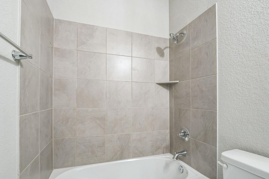 Bathroom with a textured wall, toilet, and shower combination Bathroom with a textured wall, toilet, and shower combination