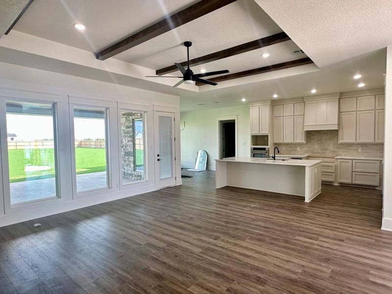 Kitchen featuring a textured ceiling, ceiling fan, a center island with sink, dark wood-type flooring, and open floor plan