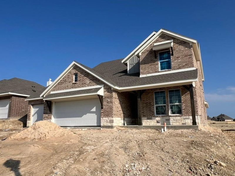 View of front of house featuring brick siding, a shingled roof, a porch, and an attached garage