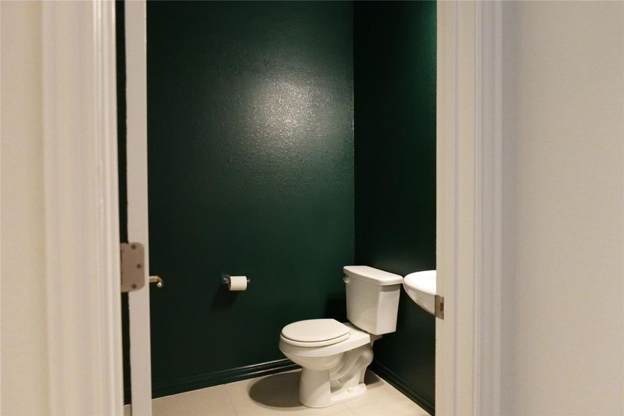 A compact powder room with striking dark walls offers convenience and a bold design.