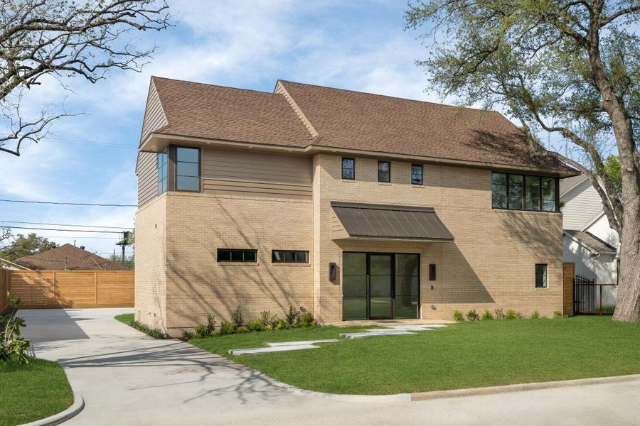 This modern two-story home features a brick exterior with large windows, a sloped roof, and a landscaped front yard. The driveway leads to a wooden privacy fence, offering a blend of style and functionality.