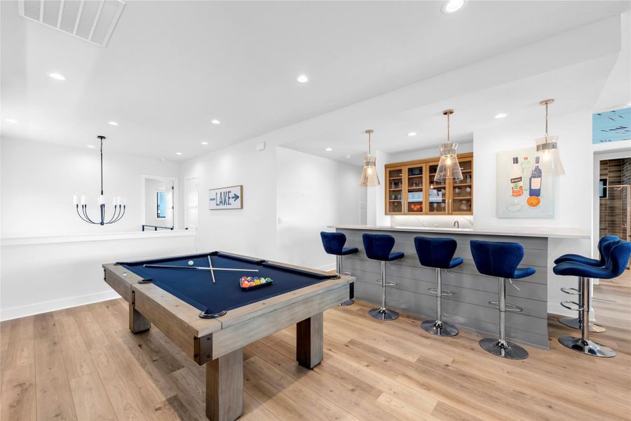 Smooth wood floors and recessed lighting anchor this inviting lower-level entertainment space.