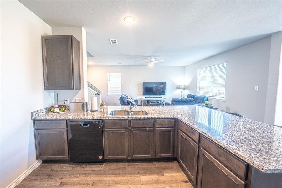 Kitchen featuring dark brown cabinetry and light stone countertops