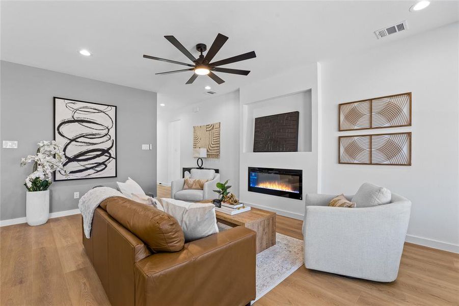 Living room featuring recessed lighting, light wood-style flooring, a glass covered fireplace, and ceiling fan Living room featuring recessed lighting, light wood-style flooring, a glass covered fireplace, and ceiling fan