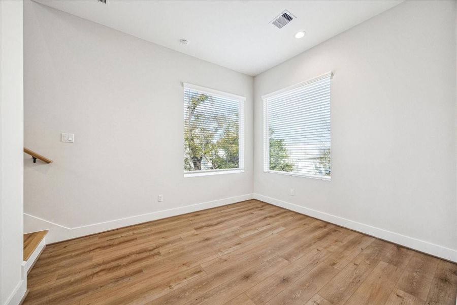 This bright dining space is filled with natural light streaming through two large picture windows—perfect for memorable meals.