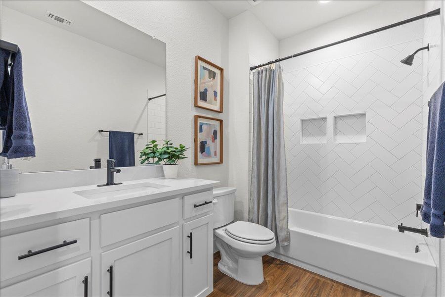 Full bath featuring dark wood finished floors, vanity, and shower / bath combination with curtain